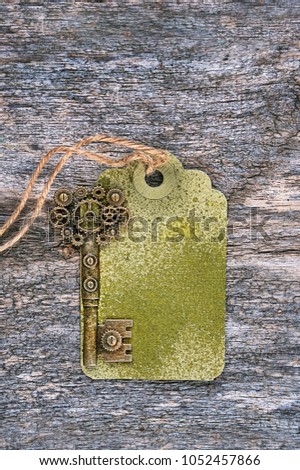 vintage key in steampunk style and  paper tag on rustic wooden background. Flat lay