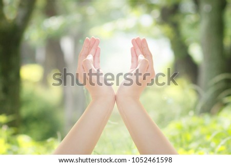 The light in young woman hands in cupped shape. Concepts of sharing, giving, offering, taking care, protection