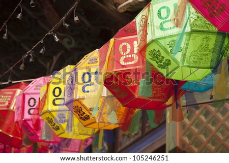 A string of colored paper lanterns hang over the outside entrance to the Buddhist temple of Bongeunsa in Seoul, South Korea. Royalty-Free Stock Photo #105246251