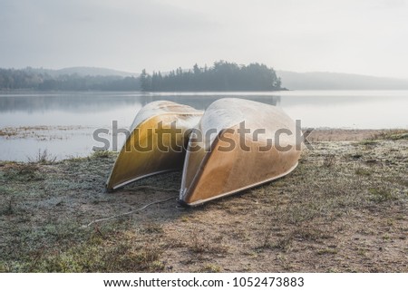 Two Canoes on the Shoreline of a Lake during Sunrise in Algonquin Park, Canada. 
