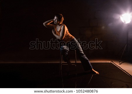 Woman in a yellow t-shirt in a dark Studio illuminated by colored spotlights during photoshoot