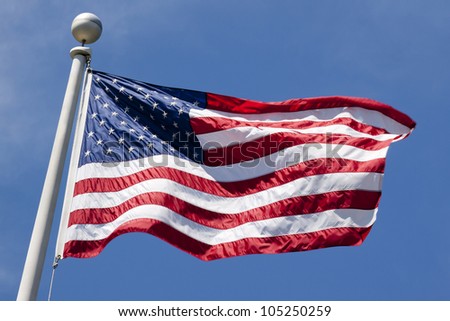 The American flag waving against a blue sky background
