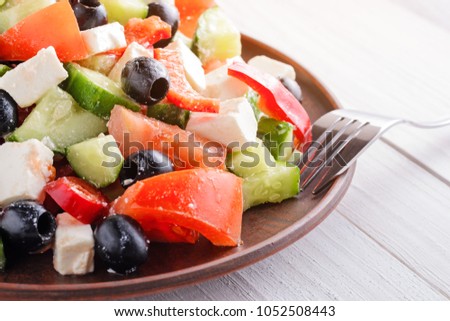 Greek salad with tomatoes, feta and olives on a wooden background, close up. Vegetarian healthy food