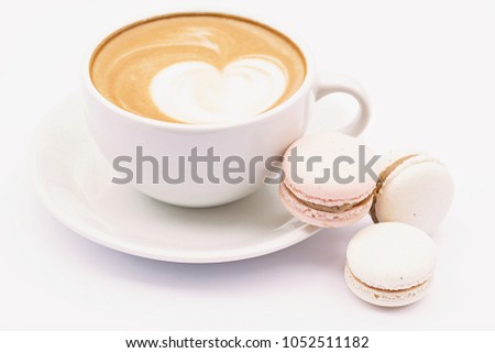 Coffee latte in a white mug and dessert macaroons on a white background.