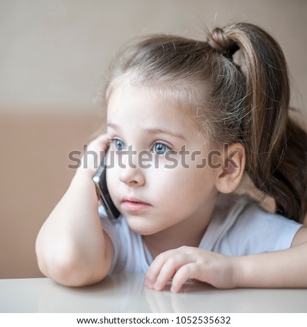 Portrait of cute little girl using cell phone talking