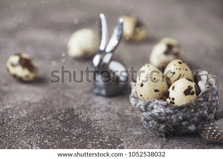 Happy easter! Little rabbit with colored quail eggs in the nest