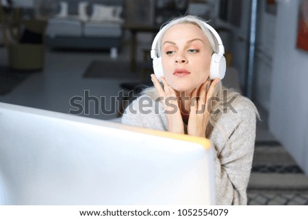 Music lover. A woman with headphones on her ears working at the computer.