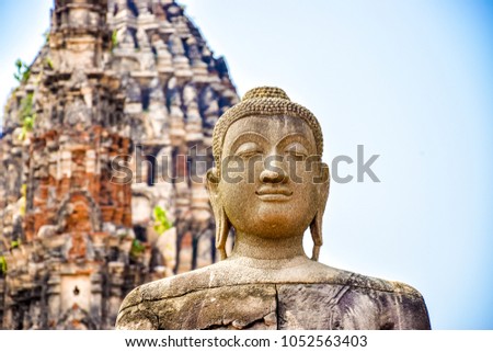 Closeup picture of a Buddha statue with an ancient temple in the background, Ayutthaya, Chai Watthanaram Temple, Thailand