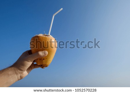 man holding a a coconut on the beach on blue sky background