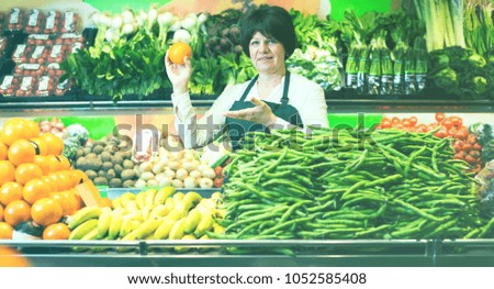 Portrait of adult female selling fruits and vegetables on the store
