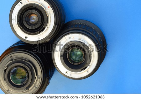 Several photographic lenses lie on a bright blue background. Space for text
