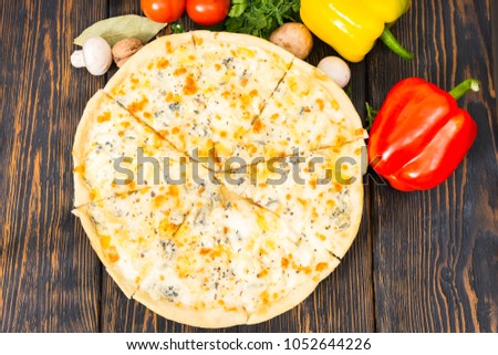 High angle view of vegetables, dill and parsley around pizza four cheeses on wooden desk