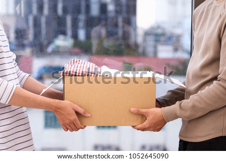 Man holding a book and clothes donate box. Donation concept. Royalty-Free Stock Photo #1052645090