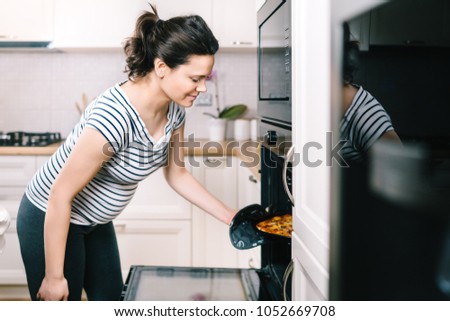 Portrait of beautiful pregnant wife preparing pizza and cooking dinner