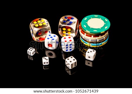 Poker chips and dice isolated on the black background .
