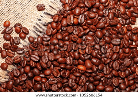 Grains of tasty roasted coffee on the background of cloth burlap