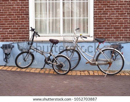Bicycles are stopping beside brick wall with white glass window