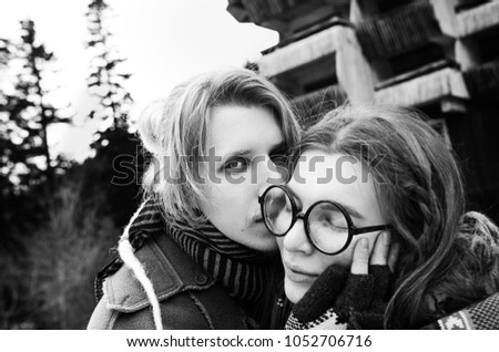 a hippy couple in love - a guy with dreadlocks and a girl with glasses and ethnic clothes and a hat hugging, black and white photo