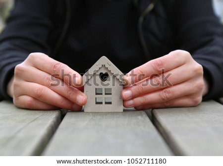 real estate and mortgage investment. Female holding a  house on the wooden background.