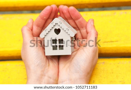real estate and mortgage investment. Female holding a house in the hand on the yellow wooden background.