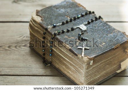 old holy bible and rosary beads on rustic wooden table