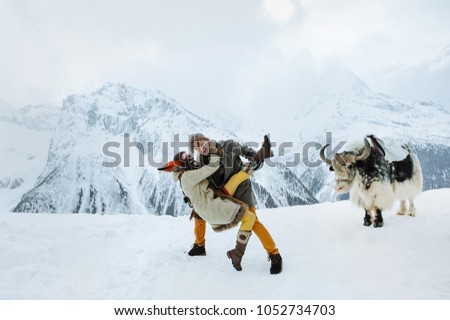 a loving couple in ethnic clothes dance against the background of snow mountains and yak