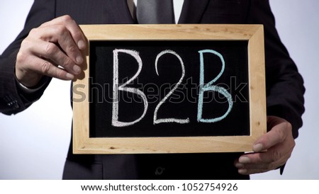 B2B, business-to-business rule written on blackboard, man holding sign, sales