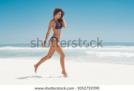 Happy smiling woman jumping on the beach. Beautiful young woman running on tropical beach. Happy latin girl walking on white sand beach during summer vacation with copy space.