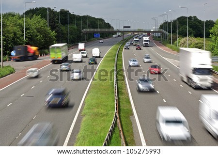 Heavy traffic moving at speed on the M6 motorway in England Royalty-Free Stock Photo #105275993