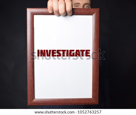 In the hands of a businessman a frame with the inscription:INVESTIGATE