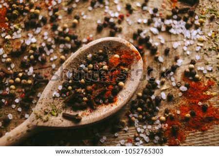 Black and white pepper peas, sea salt, red pepper powder, cloves, spices in a spoon on a wooden background. Various colorful spices close up background. Selective focus. vintage photo processing