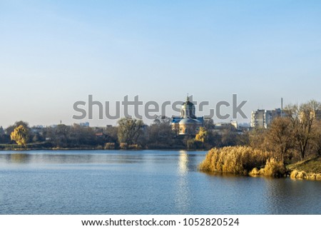 Wide river on a sunny autumn day. Multi-storey buildings and church across the river. Cityscapes and skyline in a clear blue sky on the view from the river