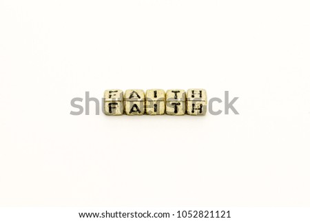 Golden cube beads with inspirational text faith on white background.