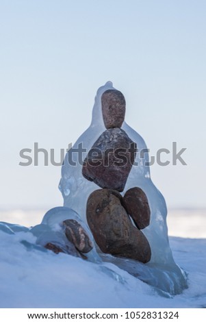 stones stacked in a balanced pyramid on one side with ice formed by frost, wind and water