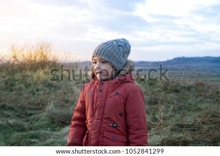Side view portrait of little boy standing alone at the mountains with sun light in evening, Lonely  4 years playing a lone outside in the gloomy day, Child looking up at sky