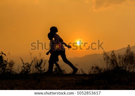 Silhouette happy two little girl playing at sunset background