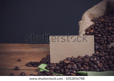 Coffee beans in sack on table wood with business card, black background. vintage style.