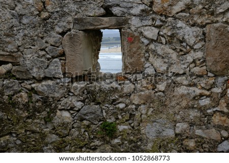 Ancient stone wall with a small window facing the sea
