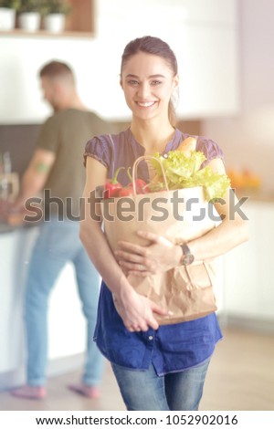 Young couple in the kitchen , woman with a bag of groceries shopping