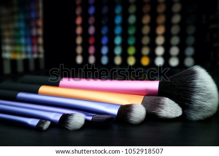 Makeup brushes and eyeshadows. Selective focus. Colorful make up artist background.