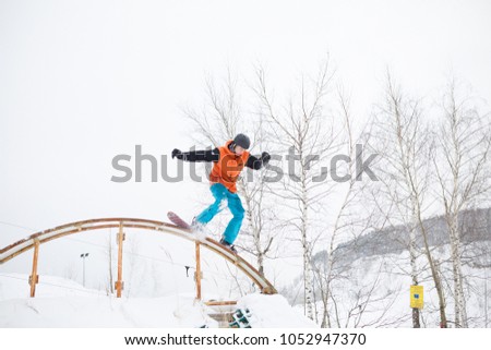 Image of athlete skating on snowboard from springboard against background of trees