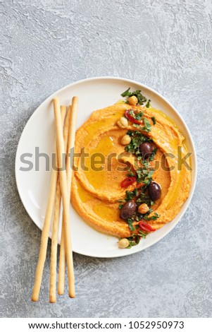 Hummus. Sweet potato, pumpkin or carrot Hummus served seasoned with olives, herbs, extra virgin olive oil and paprika. Overhead view, copy space Royalty-Free Stock Photo #1052950973