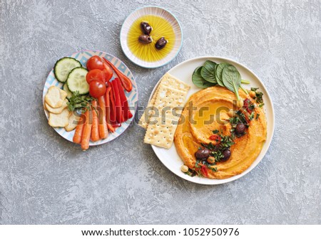 Hummus. Sweet potato, pumpkin or carrot Hummus served with fresh vegetables, seasoned with olives, herbs, extra virgin olive oil and paprika. Overhead view, copy space Royalty-Free Stock Photo #1052950976