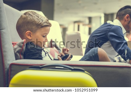 Little boy sitting in hotel hallway and playing video games. 