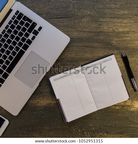 Top view of  table or desk with laptop, blank notebook, pen and smart phone on old bronze background with copy space for text.