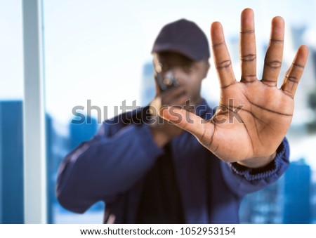 Digital composite of Security guard with walkie talkie and hand in front against blurry window showing city