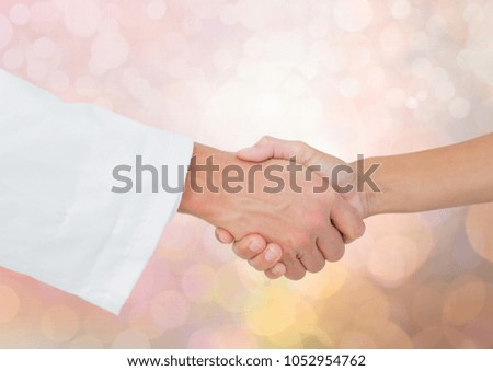 Digital composite of Hands shaking with sparkling light bokeh background
