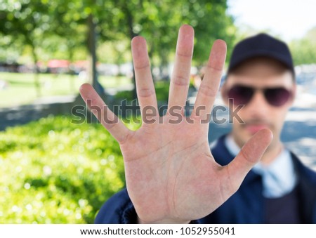 Digital composite of blurred security guard saying stop with his hand in the park