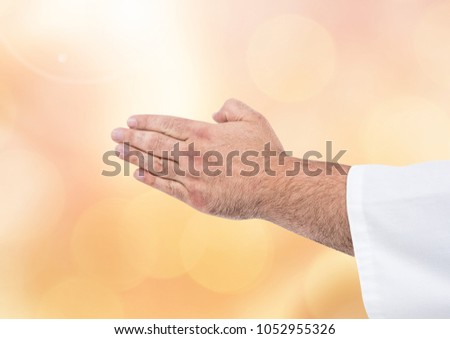 Digital composite of Hands together praying meditating with sparkling light bokeh background