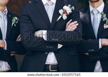 stylish groom in suit posing with groomsmen in garden on wedding day. luxury men in  rich outfits standing together. friendship Royalty-Free Stock Photo #1052957165